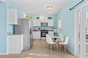 a kitchen with white cabinets and a table and chairs at Gorgeous Apartment on Mango St Steps to Beach in Fort Myers Beach