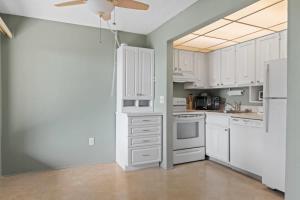 a kitchen with white cabinets and a ceiling fan at Comfy Waterfront Condo at Tennisplace Sanibel in Sanibel