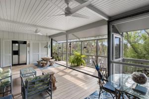 a screened porch with a ceiling fan and a glass table at Colonel's Cottage- Sanibel Beach Retreat Fantastic Amenities in Sanibel