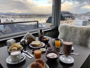 a table with breakfast foods and drinks and a window at Lennox Ushuaia in Ushuaia