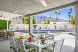 a white table and chairs on a patio with a pool at Serenity Palms- Gorgeous Villa in Palm Springs in Palm Springs