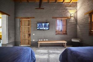 a room with two beds and a bench and a tv at Casa Estrella Malinalco in Malinalco