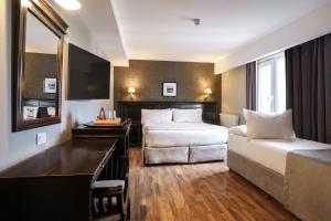 Habitación de hotel con 2 camas y sofá en Lennox Ushuaia en Ushuaia