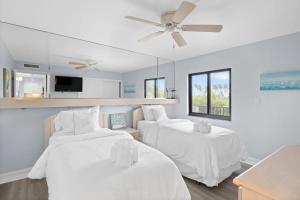 a white room with two beds and a ceiling fan at Loggerhead 253- Beachfront Residence w Vaulted Ceilings in Sanibel