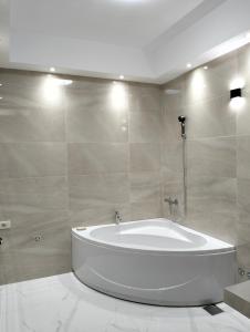 baño con bañera blanca y azulejos en Delux studio Jovana, en Tivat