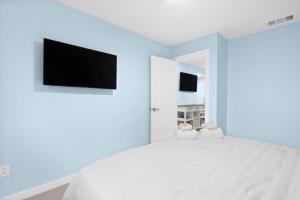 a bedroom with a white bed with a tv on the wall at Stunning Newly Renovated River District Residence in Fort Myers +8 photos