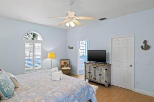 a bedroom with a bed and a flat screen tv at Mango Margarita- Beach Home with Pool Sleeps 12 in Fort Myers Beach