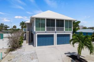 a house with a garage and a palm tree at Mango Margarita- Beach Home with Pool Sleeps 12 in Fort Myers Beach