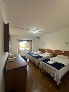a hotel room with three beds and a desk at Hotel Modena - São José dos Campos in São José dos Campos