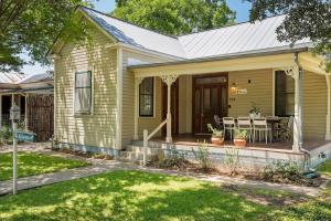 a green house with a porch with a table and chairs at The Ressman Haus at MarktPlatz with Hot Tub in Fredericksburg