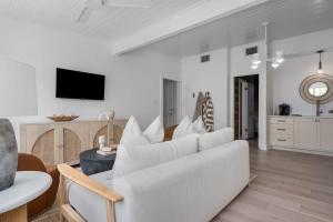 a living room with a white couch and a tv at The Ressman Haus at MarktPlatz with Hot Tub in Fredericksburg