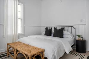 a white bedroom with a large bed with black pillows at The Ressman Haus at MarktPlatz with Hot Tub in Fredericksburg