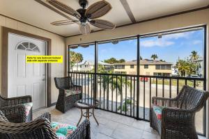a balcony with chairs and a ceiling fan at Gorgeous Beach Condo with Pool Spa and Bikes in Fort Myers Beach