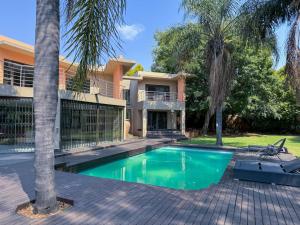 a villa with a swimming pool in front of a house at Fullbliss Guesthouse in Johannesburg