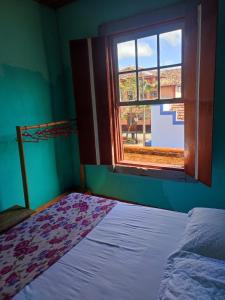 1 dormitorio con cama y ventana en Casa Centenária localizada no coração da cidade, en São Luís do Paraitinga