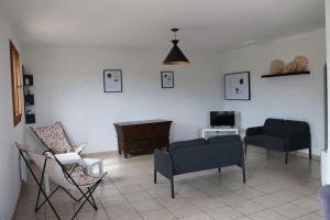- un salon avec des chaises, un canapé et une table dans l'établissement Agréable villa - proche commodités mer et montagne, à Afa