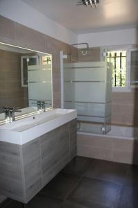 La salle de bains est pourvue d'un lavabo, d'un miroir et d'une baignoire. dans l'établissement Agréable villa - proche commodités mer et montagne, à Afa