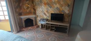a room with a fireplace and a tv on a wall at CHALES Canto dos Pássaros in Monte Verde