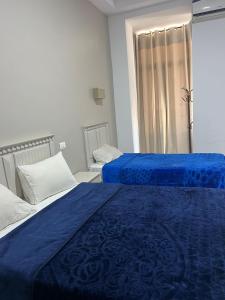 a bedroom with two beds with blue sheets and a window at Hotel Transatlantique Tunis in Tunis