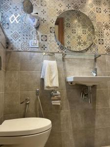 ein Badezimmer mit einem WC, einem Waschbecken und einem Spiegel in der Unterkunft Hotel Transatlantique Tunis in Tunis