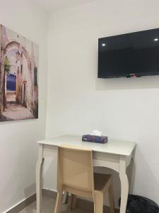 una scrivania bianca con una televisione su un muro di Hotel Transatlantique Tunis a Tunisi