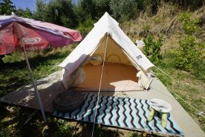 a tent with a mattress and a chair in a field at Rifugio tra gli alberi in Atri