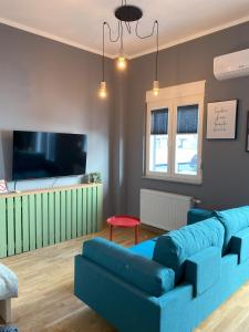 ein Wohnzimmer mit einem blauen Sofa und einem Flachbild-TV in der Unterkunft 021 Hideout in Novi Sad