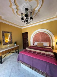 a bedroom with a large bed and a chandelier at Hotel La Casa de María Joyita in Aguascalientes