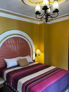 ein Schlafzimmer mit einem großen Bett mit einem Kronleuchter in der Unterkunft Hotel La Casa de María Joyita in Aguascalientes