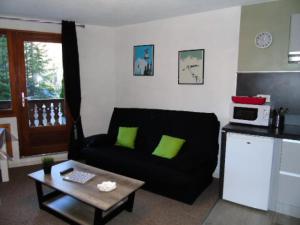 un soggiorno con un divano nero e un tavolo di Résidence Chamois - Studio pour 4 Personnes MAE-9324 a Modane