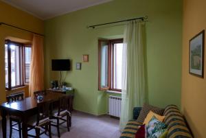 a living room with green walls and a table and a couch at Appartamento Talia in Bevagna