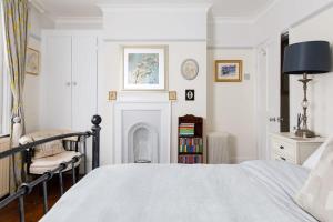 a white bedroom with a bed and a fireplace at Beautiful Georgian Home in the heart of Chichester in Chichester