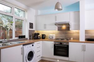 a kitchen with white cabinets and a washer and dryer at Stunning 4br House for 10 Near Beach w Hot Tub in Bognor Regis