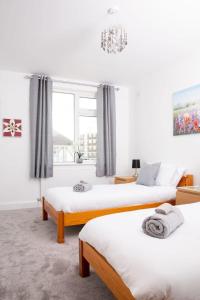 a bedroom with three beds and a window at Stunning 4br House for 10 Near Beach w Hot Tub in Bognor Regis