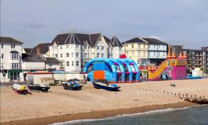 um parque infantil numa praia com edifícios ao fundo em Stunning 4br House for 10 Near Beach w Hot Tub em Bognor Regis