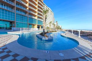 a swimming pool with a palm tree in front of a building at Luxury Gulf Front Condo Lazy River 704 in Orange Beach