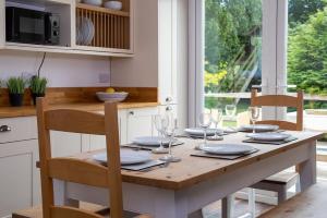 - une table en bois avec des assiettes et des verres à vin dans l'établissement Lux Countryside Haven Mins to Beach Garden, à Birdham