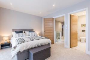 a bedroom with a large bed and a bathroom at Stylish new home with parking - king beds garden in Chichester