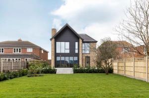 a house with a fence and a grass yard at Stylish new home with parking - king beds garden in Chichester