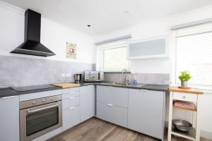 a kitchen with white cabinets and a sink at Bright & modern Sussex seafront home Great views in Selsey +36 photos
