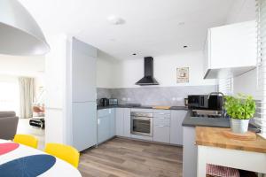 a kitchen with white cabinets and a counter top at Bright & modern Sussex seafront home Great views in Selsey