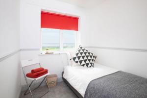 a small bedroom with a bed and a window at Bright & modern Sussex seafront home Great views in Selsey