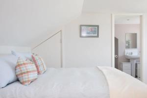 Una cama blanca con dos almohadas encima. en Seaside detached 4bd home nr shops Parking Garden en West Wittering