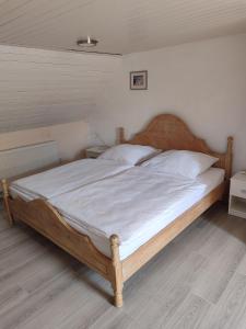 ein Schlafzimmer mit einem Holzbett, bezogen mit weißen Laken und Kissen. in der Unterkunft Gästehaus Herda in Briedel