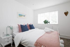 a white bedroom with a large bed and a window at Idyllic countryside annexe near West Wittering beach in West Wittering