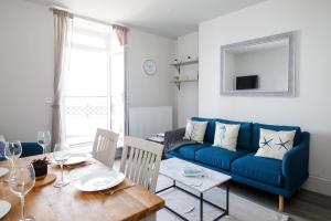 a living room with a blue couch and a table at Panoramic sea views in beachfront apt w balcony in Bognor Regis