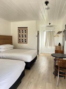 a bedroom with two beds and a table in it at Triangle Motel in Red Bluff