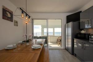 a kitchen with a wooden table and a dining room at Stunning Beachfront Apt w Balcony & Sea Views in Bognor Regis