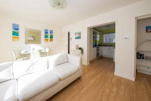 a white living room with a white couch and a kitchen at Sunny & Modern Near the Beach & Village w Parking in East Wittering