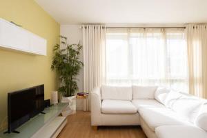 uma sala de estar com um sofá branco e uma televisão em Sunny & Modern Near the Beach & Village w Parking em East Wittering